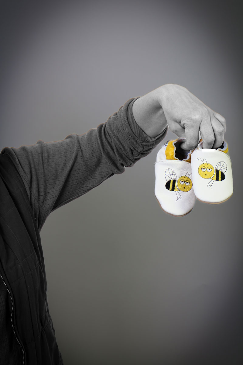 Mitarbeiterin hält Kinderschuhe in die Kamera schwarz/weiß